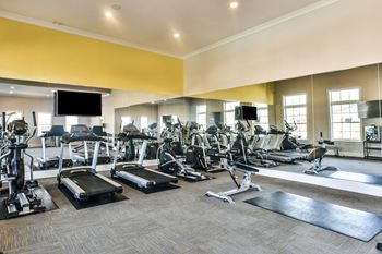 A large fitness room with cardio equipment and flat screen televisions 